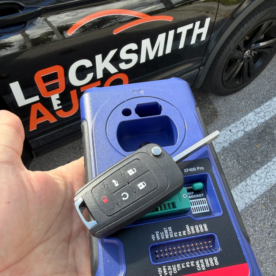 Chevrolet flip key being programmed next to a Locksmith Auto service vehicle