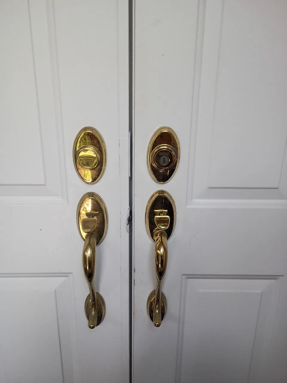 Brass handlesets and deadbolts installed on a double front door