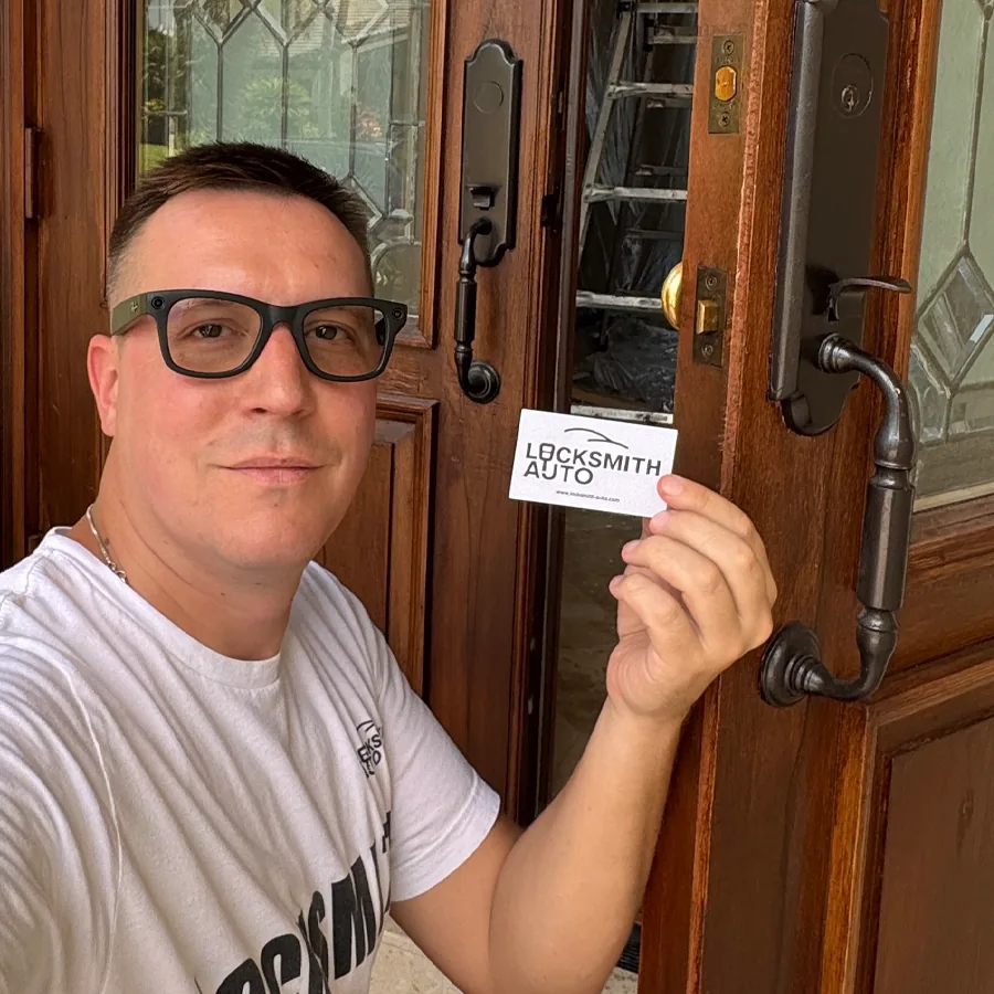 Tikhon Bukhamet, owner of Locksmith Auto, holding a Locksmith Auto business card at a customer's front door